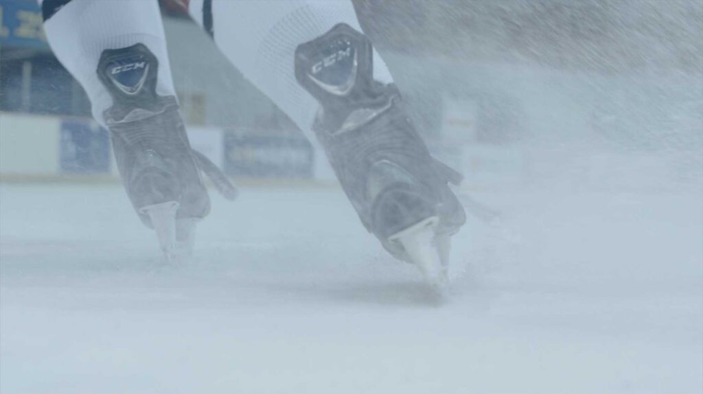 A close-up of Choa's ice skates carving into the ice as she comes to a stop, showcasing her role as the sole woman on the men’s ice hockey team in Seoul, South Korea.