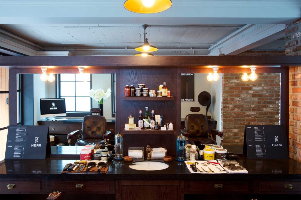 Interior of the gentlemen's barber shop HERR, featuring two vintage barber chairs and a variety of grooming tools spread out on the counter.