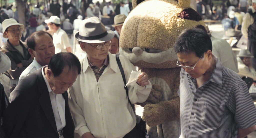 Lost cat seeks its birth mother among a group of older men in a park in Nana-D's 'Lose Against You' music video