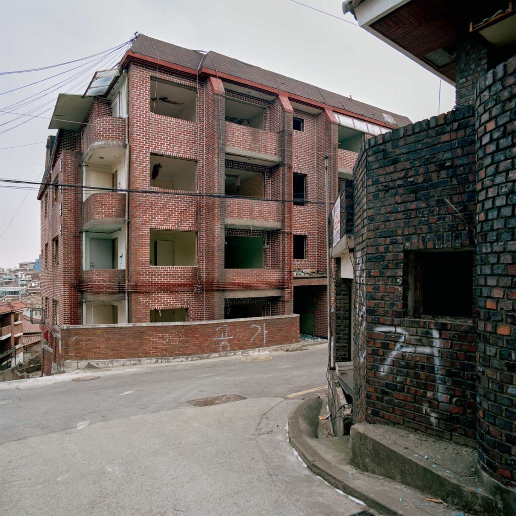 The exterior facade of an abandoned four-story building in Seoul, South Korea, stands empty with all windows removed, awaiting demolition along with the entire neighborhood