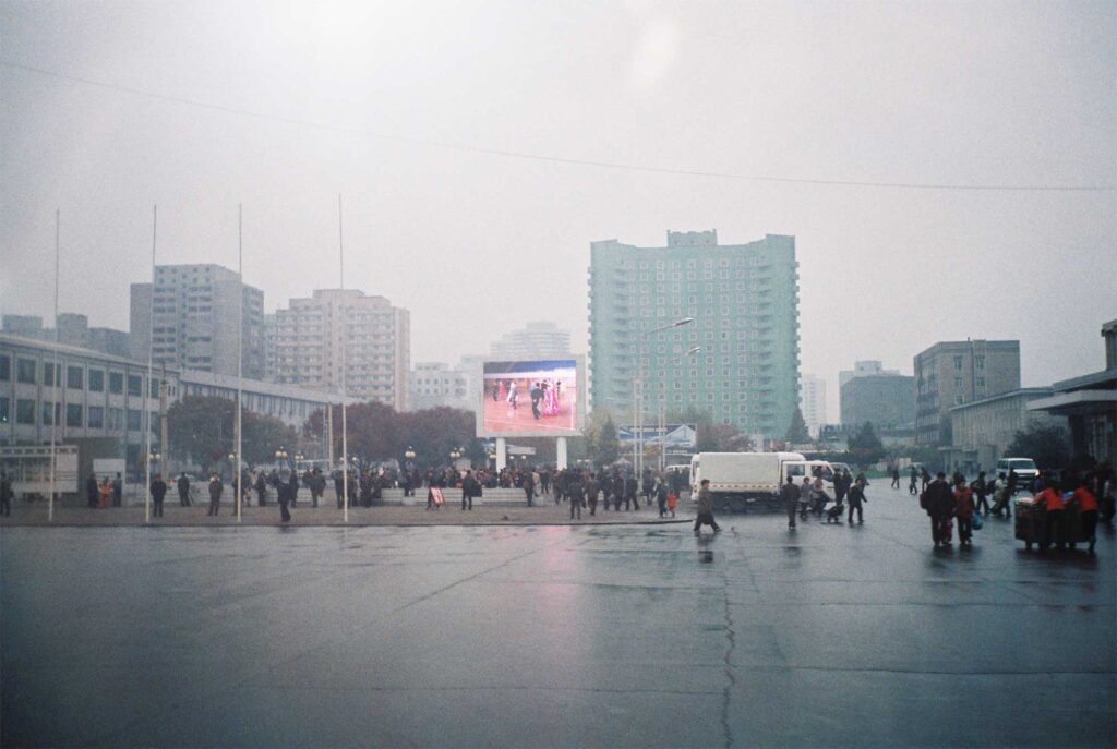 A wide square in Pyongyang, North Korea, with towering high-rise buildings in the background.