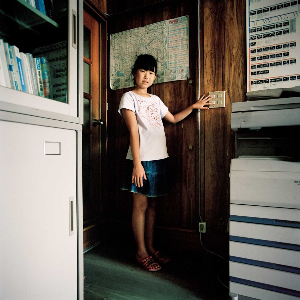 Young girl in Tokyo home, hands switch off lights to save energy