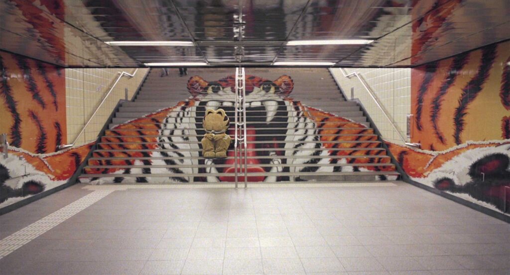 Lost cat perches near a tiger mural's open mouth at Olympic Park in Seoul, South Korea, in Nana-D's 'Lose Against You' music video
