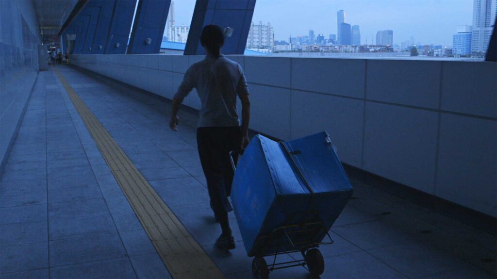 A screenshot from the Varúð music video by Icelandic band Sigur Rós, showing a homeless man collecting recyclables near Yongsan Station in Seoul's night