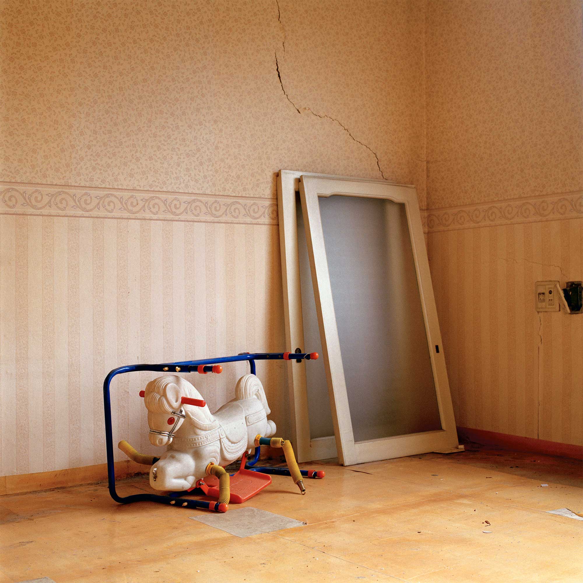 In the empty living room of an abandoned home in Seoul, South Korea, a broken plastic rocking horse sits alongside two removed window sliding doors leaned against a wall