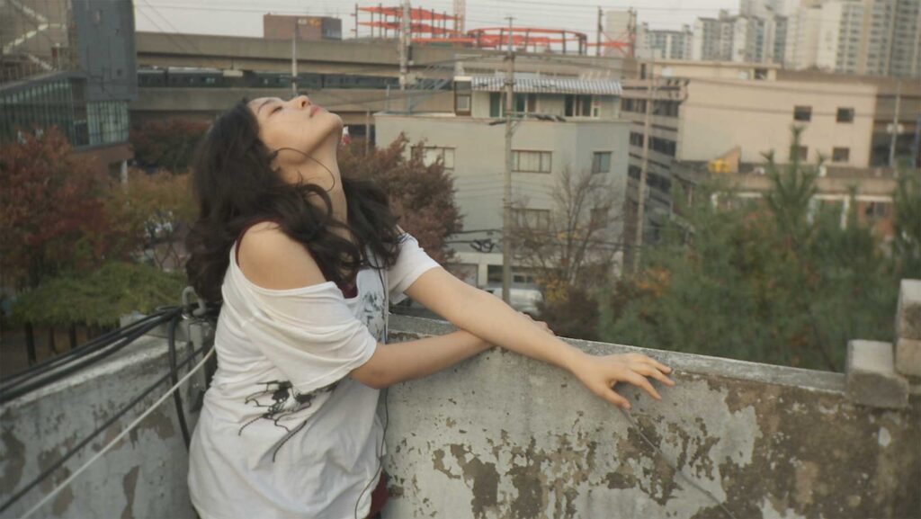 Ji-Young Moon as Joy, dancing in the rain on a rooftop during a break