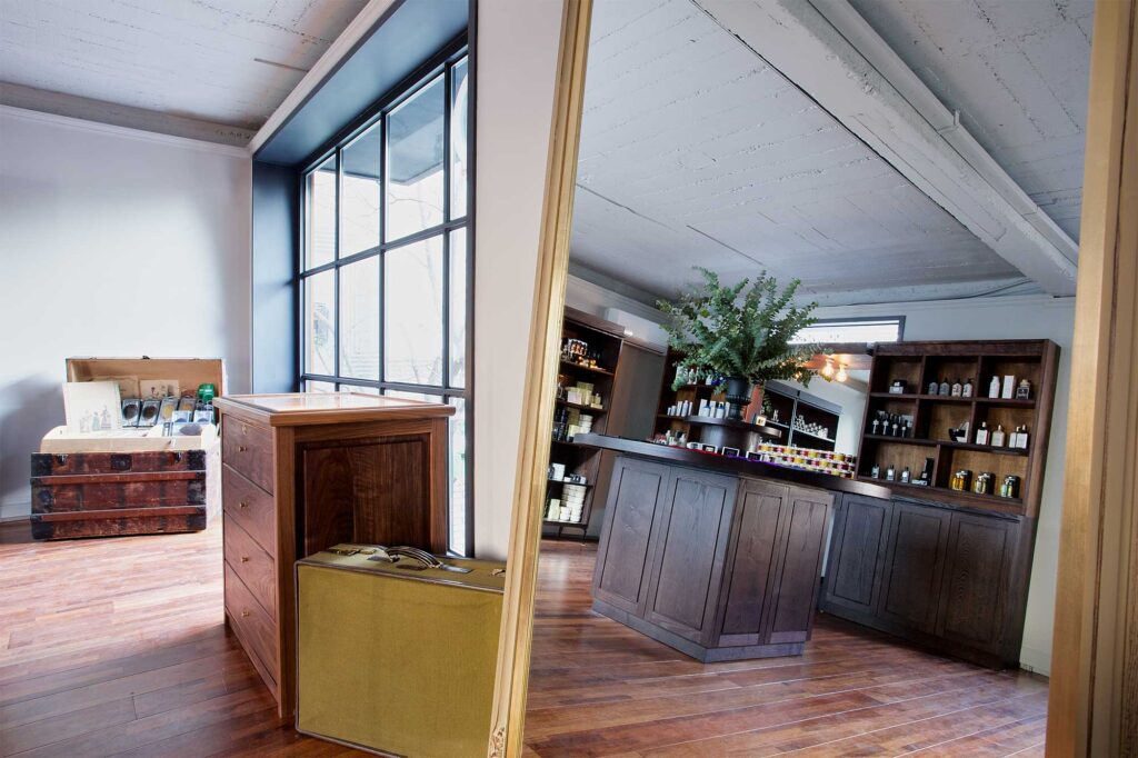 View through a reflective mirror showing the second floor accessory area of the gentlemen's barber shop HERR in Seoul, South Korea, showcasing a range of ties, buttons, creams, and oils for sale.