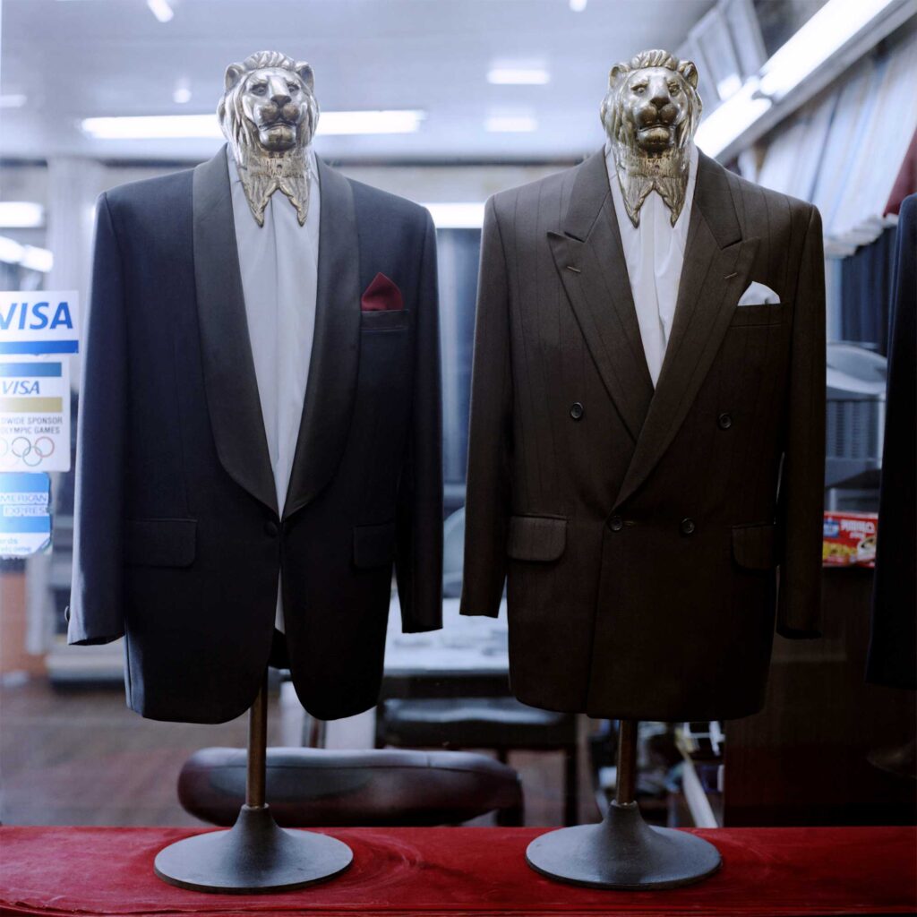 A showcase displays two stands adorned with lion's head motifs. Each stand is dressed in a tailored suit, adding a touch of elegance.