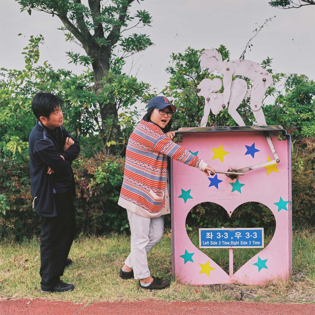 A couple operates a rotating sculpture, surprised by its action at Loveland sculpture park, Jejudo Island, South Korea