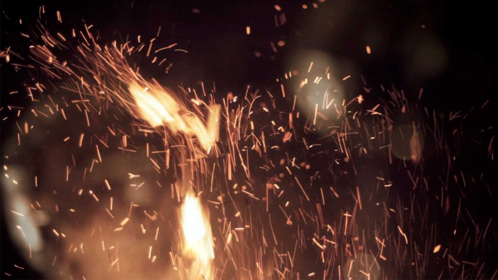 A scene from the Wolf + Lamb vs. Soul Clap 'Lonely C' music video: Outside a house in a South Korean countryside village, a campfire throws sparks up into the dark evening sky