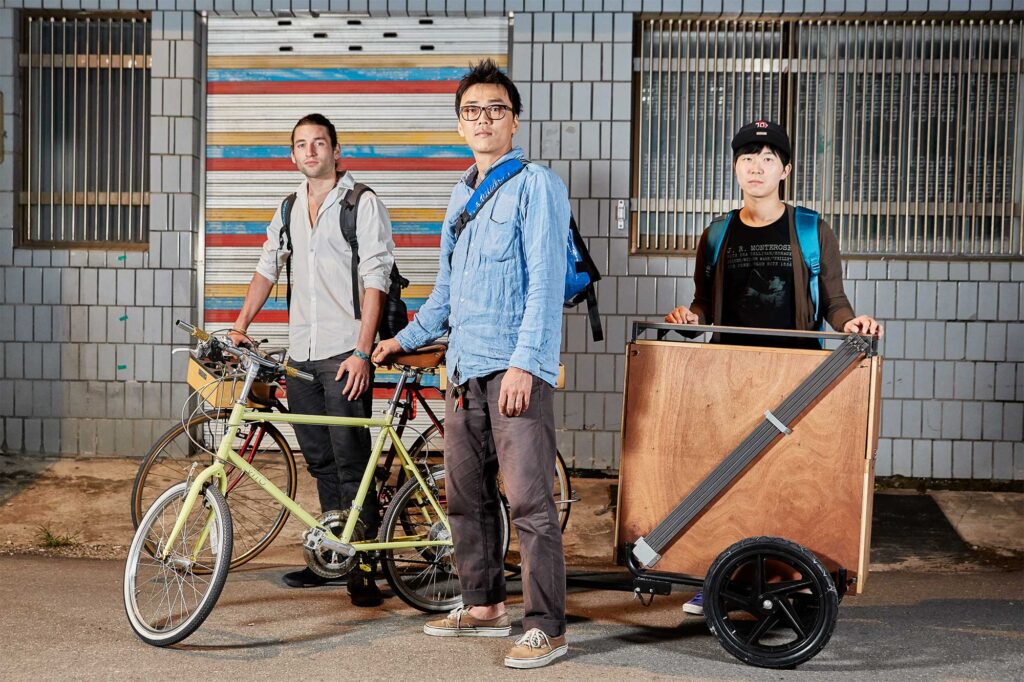 A foreigner and two Korean friends proudly present their bicycle coffee pop-up store, serving freshly brewed coffee throughout the city of Seoul