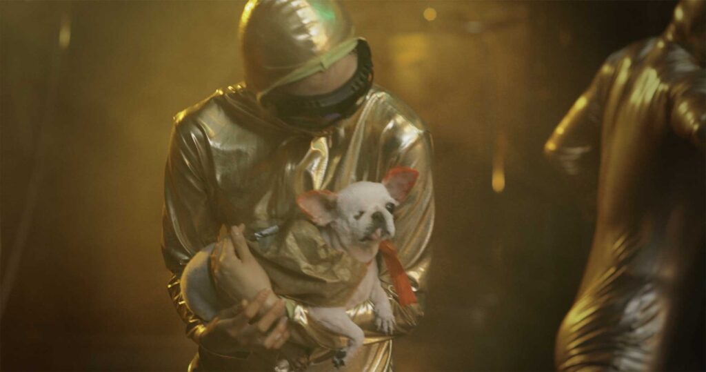 M83's Moonchild music video showing an alien dancing with a red-eared dog held on its arm.