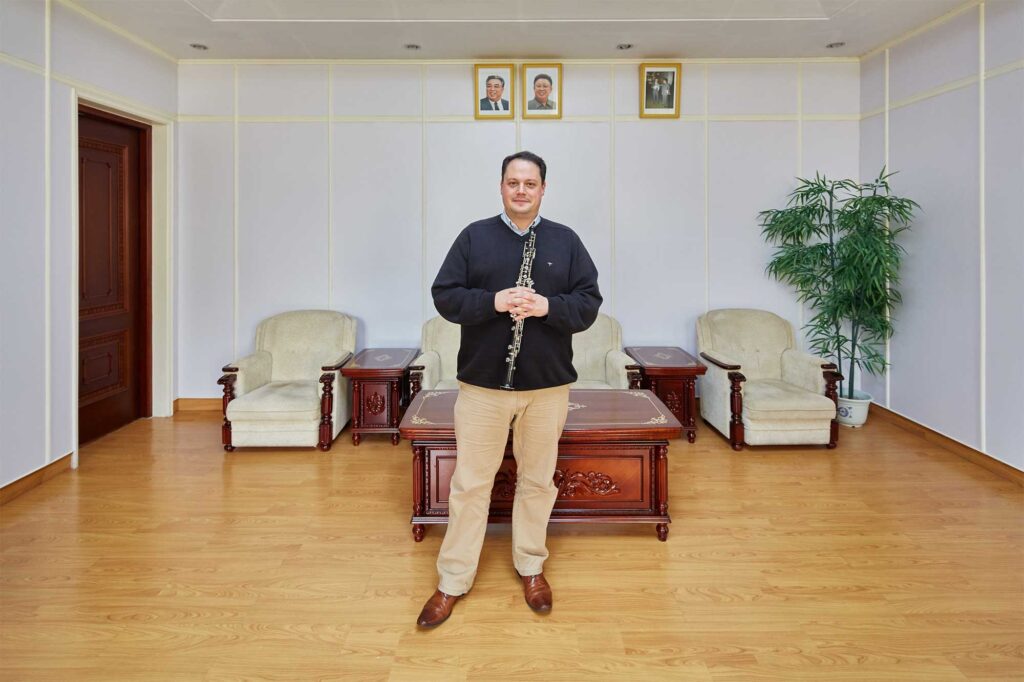 Munich Chamber Orchestra piccolo player in Pyongyang, North Korea, with portraits of North Korean leaders Kim Il-Sung and Kim Jong-Il on the wall