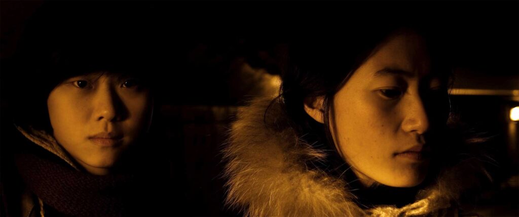 Portrait of two young Korean women illuminated by yellow tunnel light at tunnel entrance