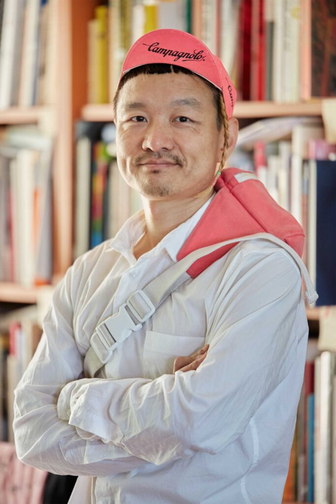 A Seoul-based mini cycle enthusiast poses in a pink retro bicycle hat, showcasing their passion for cycling.
