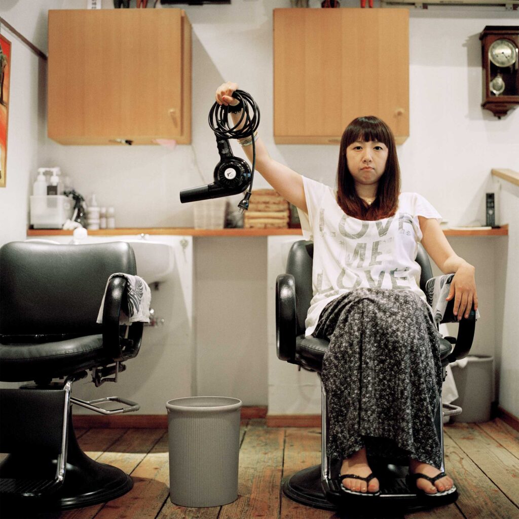 Hairdresser in Tokyo salon about to discard hairdryer, conserving energy post-Fukushima