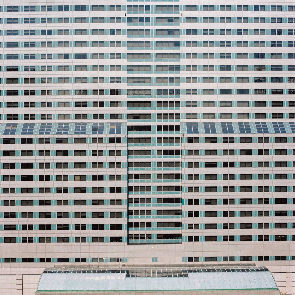 Turquoise-toned concrete facade in Gangnam district, Seoul. Rhythmic window pattern adds dynamism, forming a distinctive + shape in the building's structure