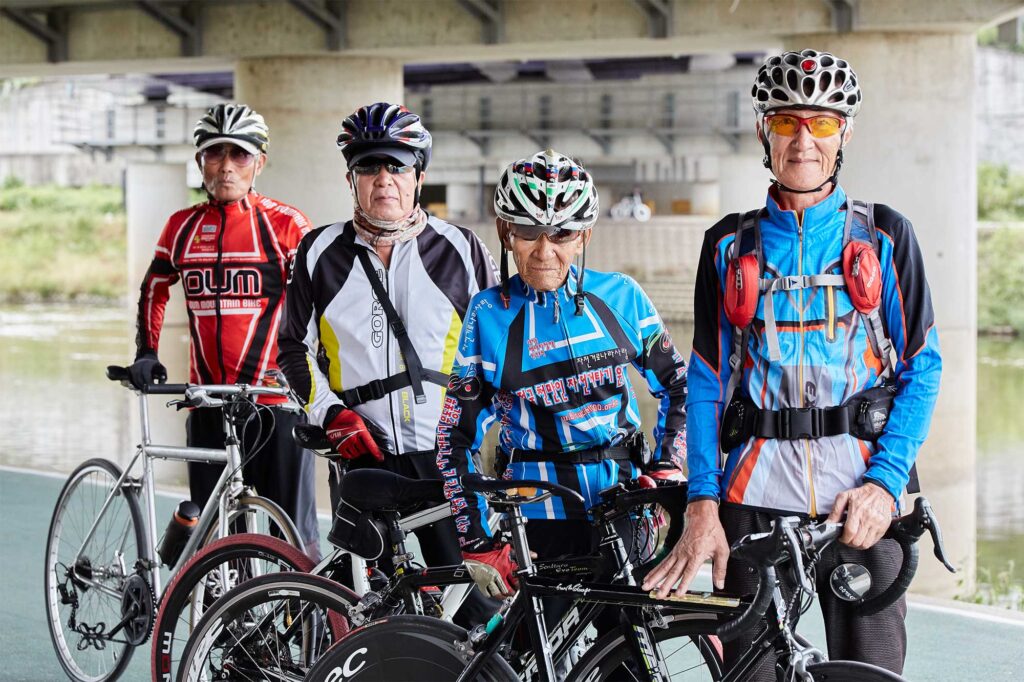 A group portrait of four senior cyclists, passionate about cycling, riding together along the Han River in Seoul every day.
