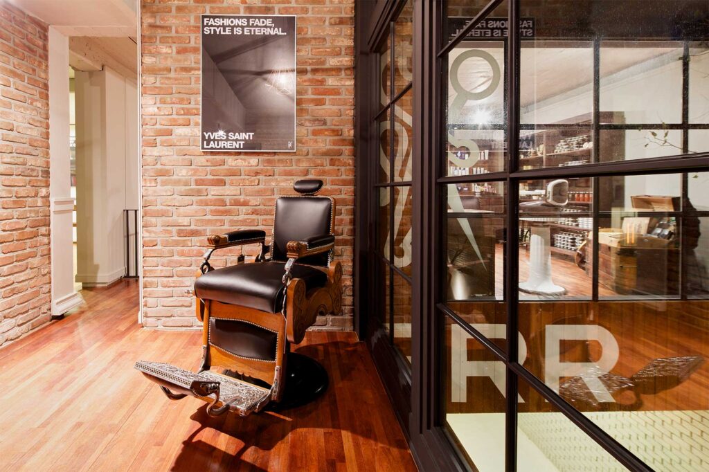 A vintage barber chair in the corner of the gentlemen's barber shop HERR in Seoul, South Korea, with the accessory sales room visible through the window in the background.