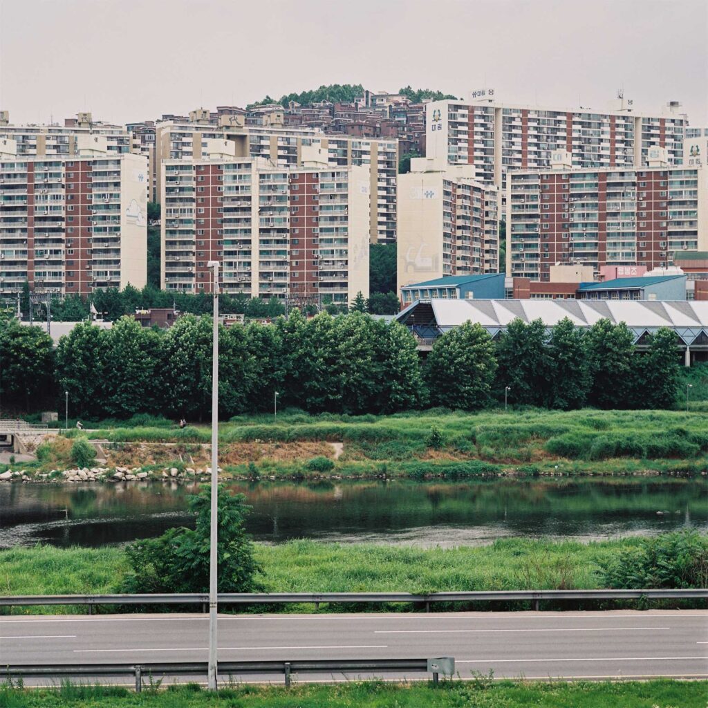 A Daldongnae (Hillside Moon Village) in Seoul, South Korea, where apartment buildings on the lower surface wrap around the hill, visually obscuring the older buildings lining the hill