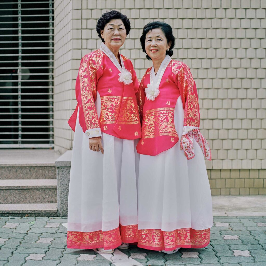 Elderly women in vibrant traditional Korean Hanbok dresses, adorned with ornamental golden print patterns