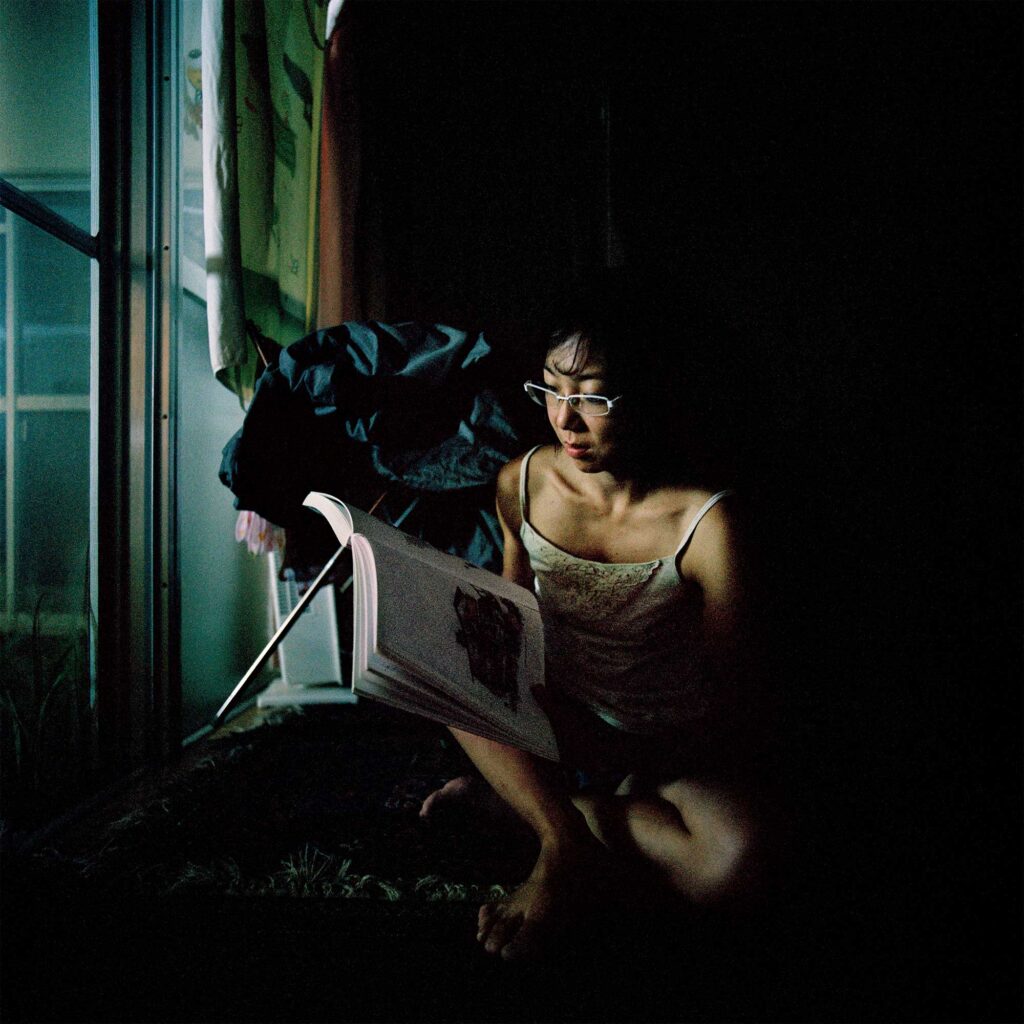 Young woman in Tokyo conserves energy post-Fukushima by reading near window light