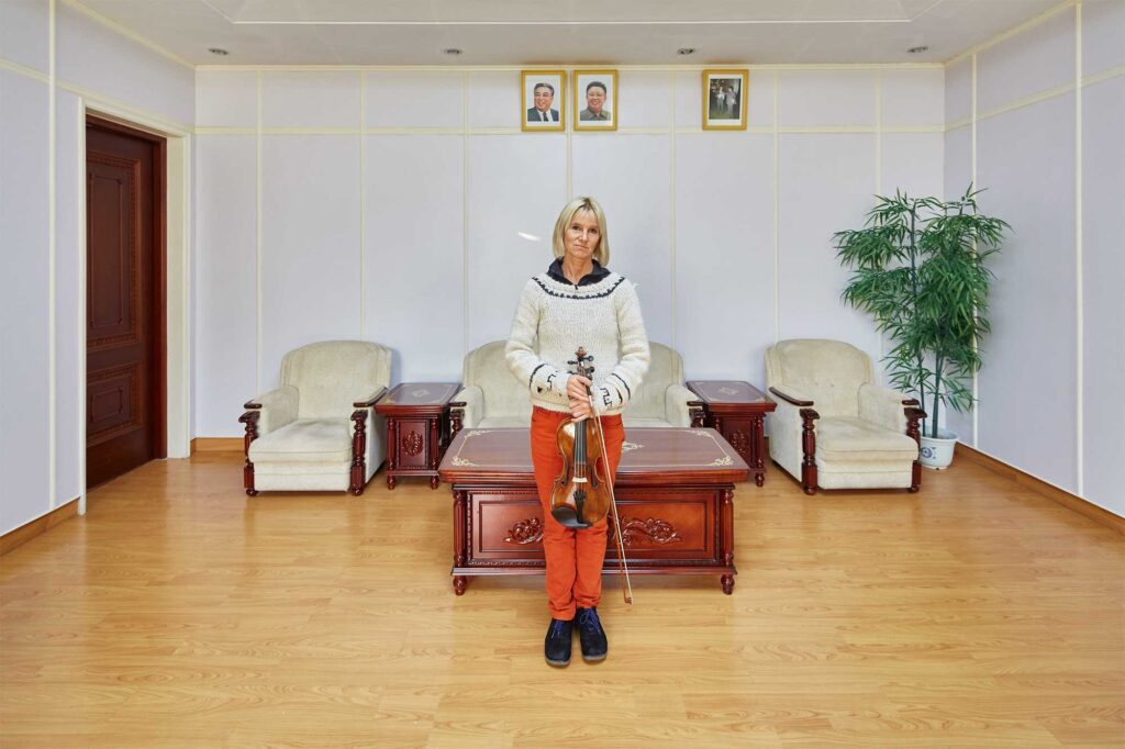 Munich Chamber Orchestra viola player in Pyongyang, North Korea, with portraits of North Korean leaders Kim Il-Sung and Kim Jong-Il on the wall