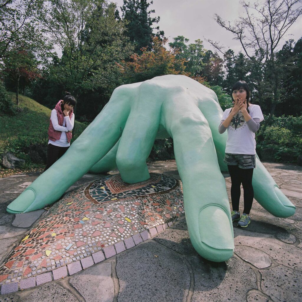 Two girls shocked in standing in between sculpture of hand during masturbation in Loveland Sculpture Park on Jejudo Island, South-Korea