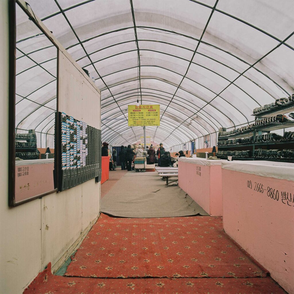 A greenhouse serves as a waiting area and ice skating shoe dressing spot next to an outdoor ice rink in Seoul's outskirts