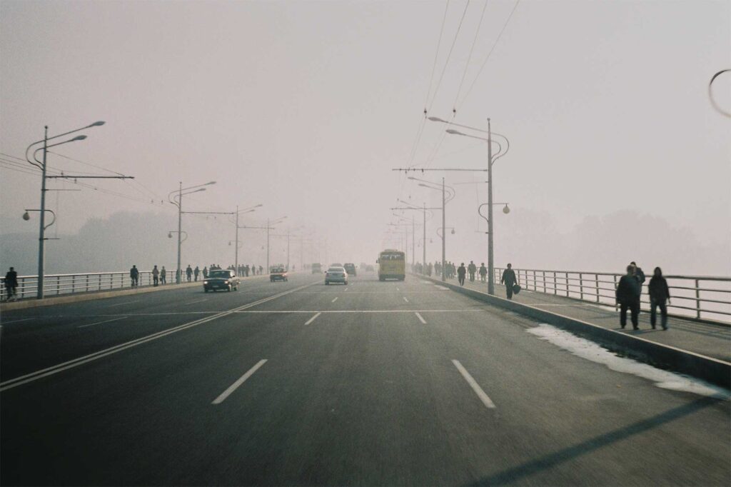 A bridge over the Taedong River in Pyongyang, North Korea, with pedestrians on the side and vehicles in the middle