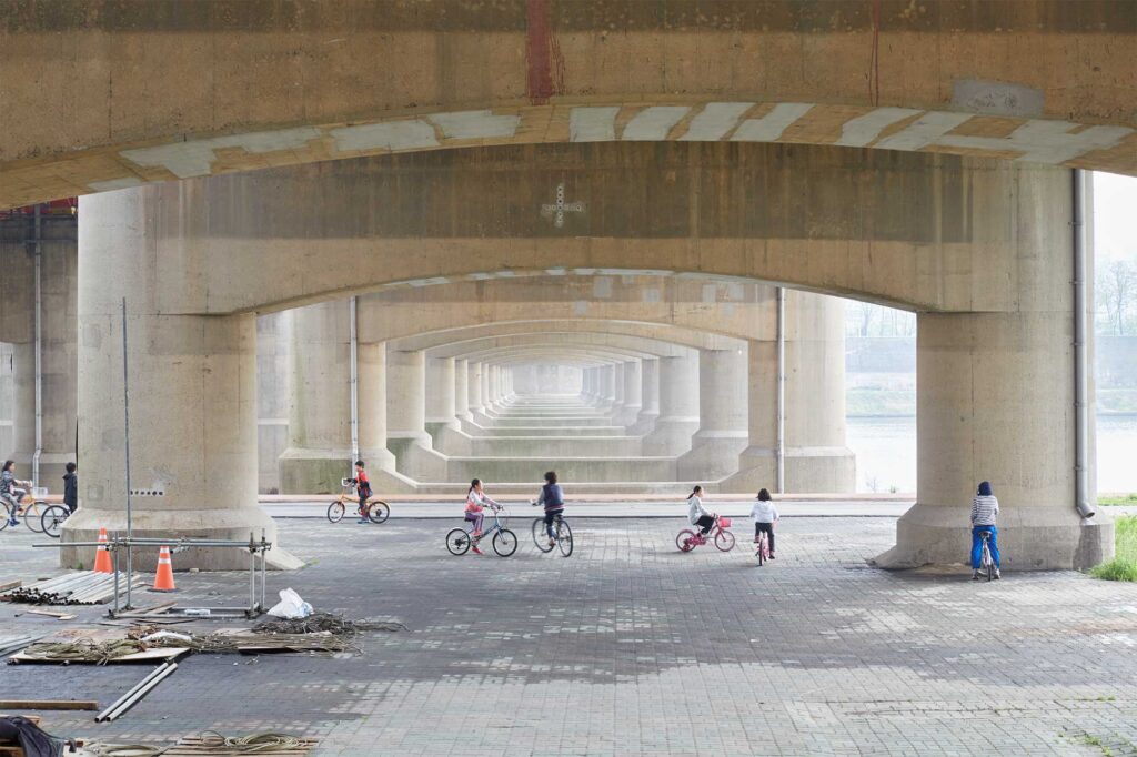 Kids playing on their bicycles under a bridge crossing the Han River in Seoul, South Korea