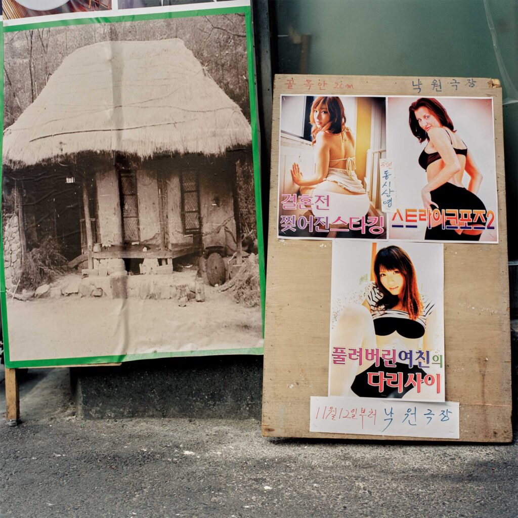 Posters for a pornographic movie theater line a Jongro wall in Seoul, South Korea, juxtaposed with a printed photo of a traditional Korean building.