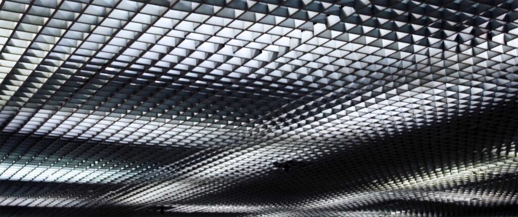 A square-patterned ceiling structure illuminated by varying intensities of light in a subway station in Seoul, South Korea