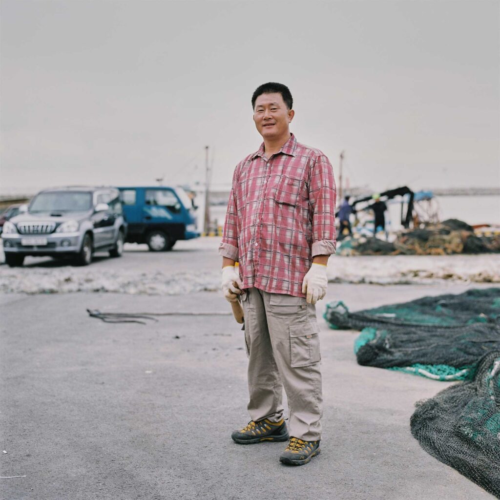A Korean fisherman on the East Coast takes a break from laying out fishing nets by the roadside to dry