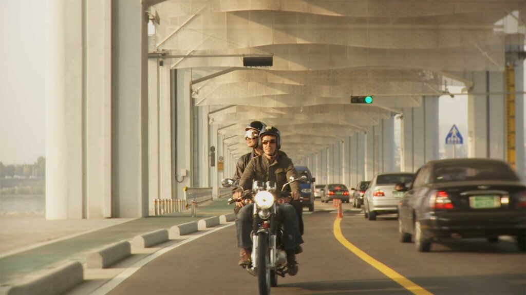 Crisjan Zollner as Lukas with Mr Lim-on a motorbike crossing Han-River in Seoul South Korea