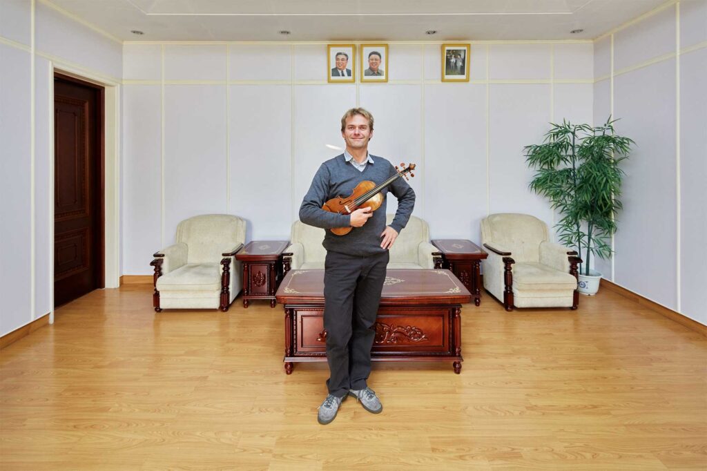 Munich Chamber Orchestra viola player in Pyongyang, North Korea, with portraits of North Korean leaders Kim Il-Sung and Kim Jong-Il on the wall