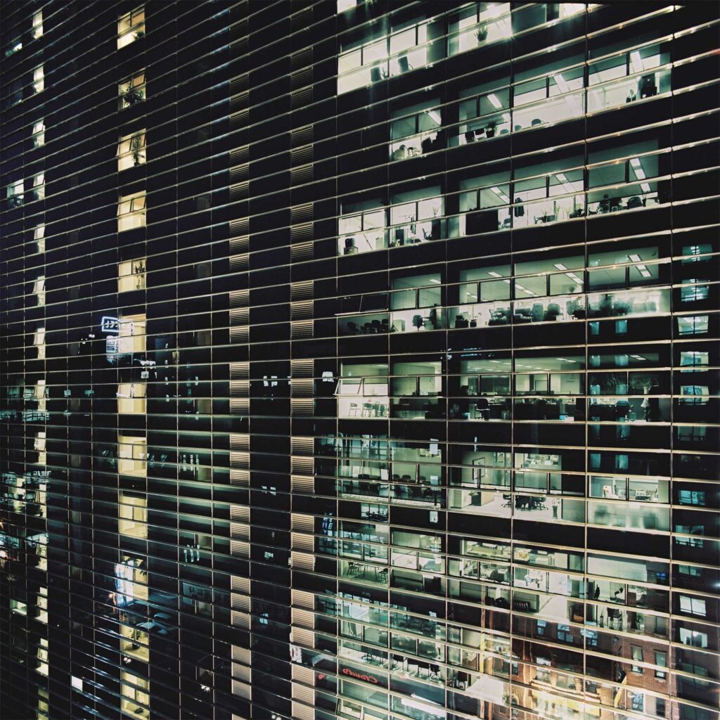 Glistening glass architecture in Gangnam district, Seoul, at night. Illuminated office interiors offer a glimpse into Seoul's bustling nighttime office scene