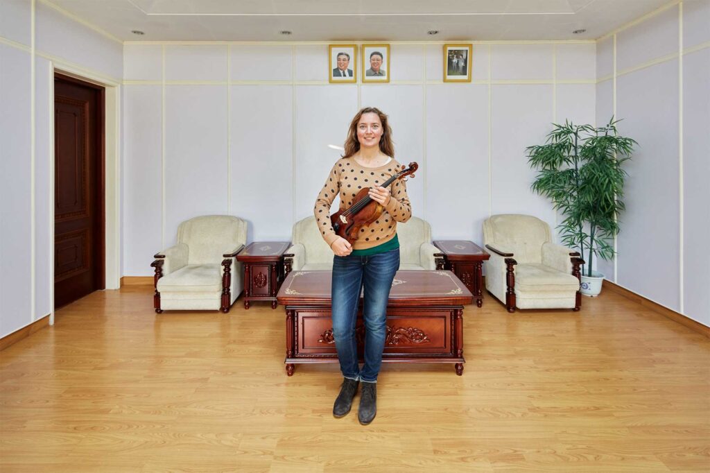 Munich Chamber Orchestra viola player in Pyongyang, North Korea, with portraits of North Korean leaders Kim Il-Sung and Kim Jong-Il on the wall