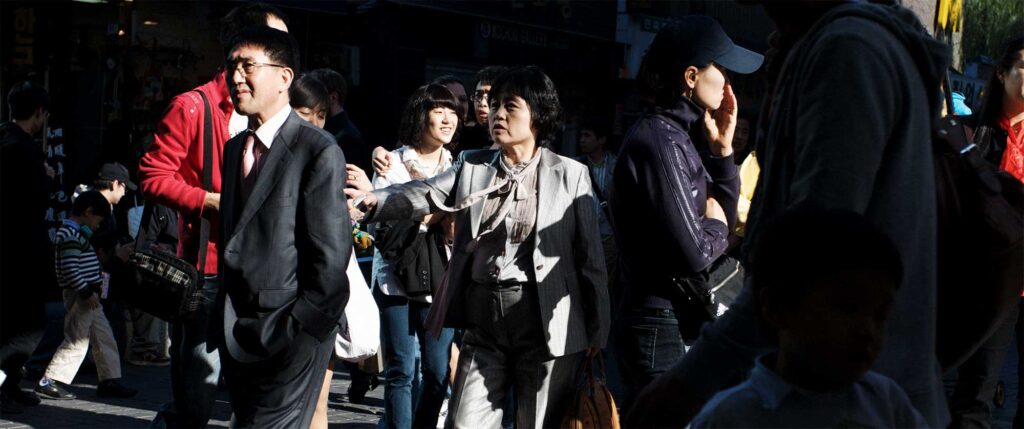 Busy street scene in Insadong, Seoul, South Korea. A man and woman are illuminated by late afternoon sunlight as they walk the streets