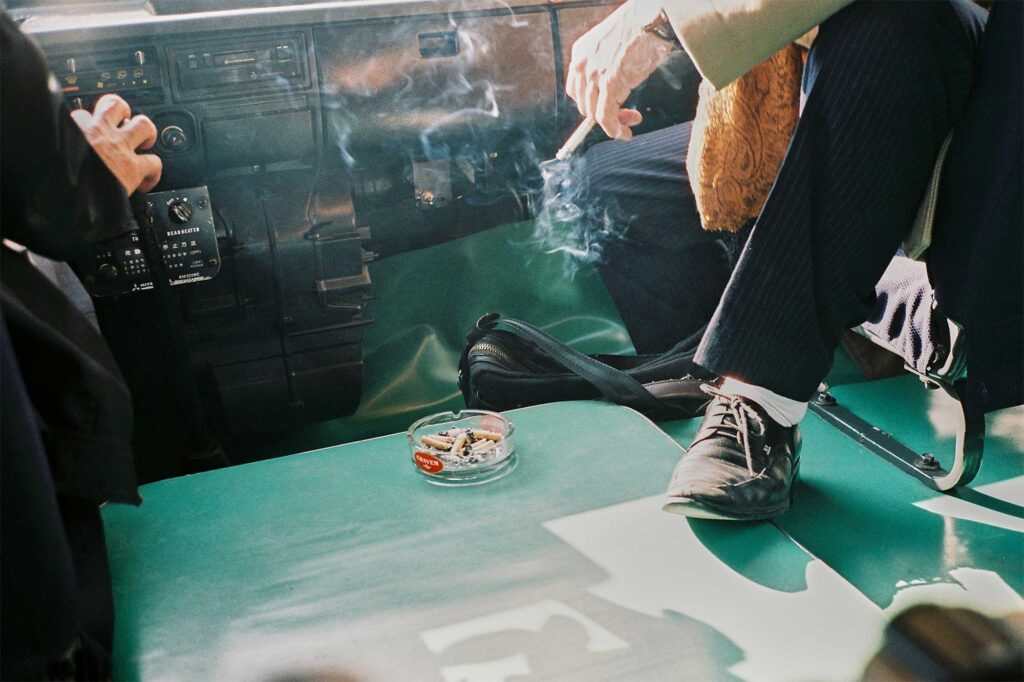 The tour guide in Pyongyang, North Korea, relaxes in the shotgun seat of the tour bus, enjoying a smoke