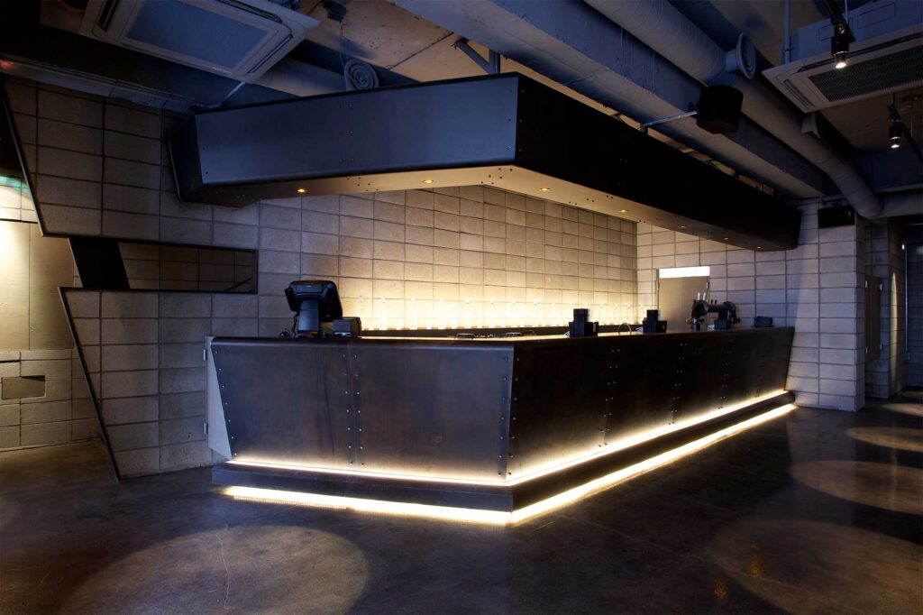 Main counter area of Warehouse bar and restaurant in Seoul, South Korea, featuring modern design with minimal decor using mainly concrete and metal.
