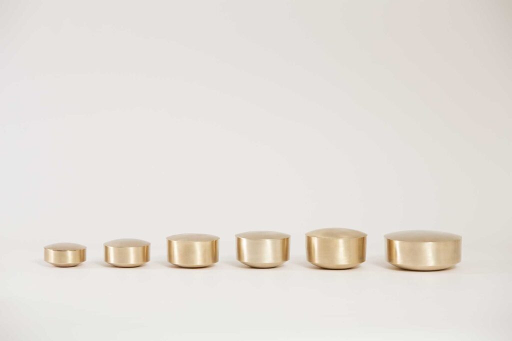 Different sized bowls of Korean traditional brass kitchenware, designed by Gio Kisang and crafted by YÉOL Artisan of the Year, Kim Soo-Young, lined up in a row.