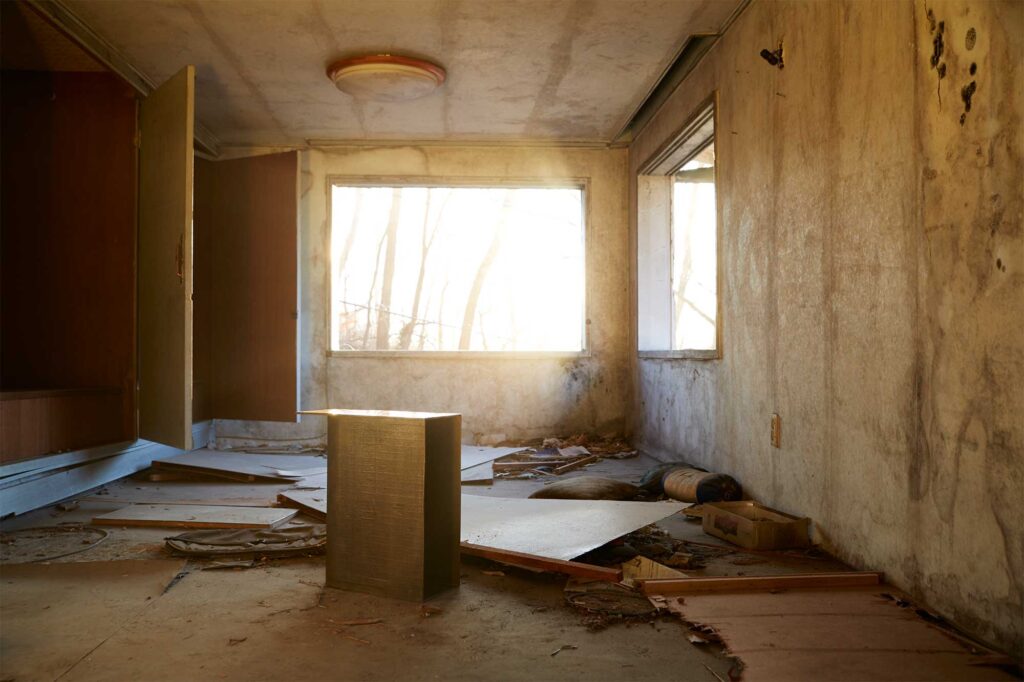 A lacquer-coated bronze furniture piece by Korean artist Kwangho Lee, winner of the 2013 YÉOL Young Craftsman Award, in an abandoned home with sunlight streaming through a large demolished window.