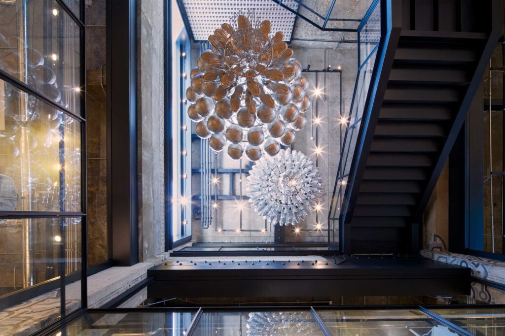 View from bottom to top, showcasing two stunning chandeliers hanging above the ground and first floors at Nike's largest store in Korea, displaying the latest sportswear in Gangnam, Seoul.