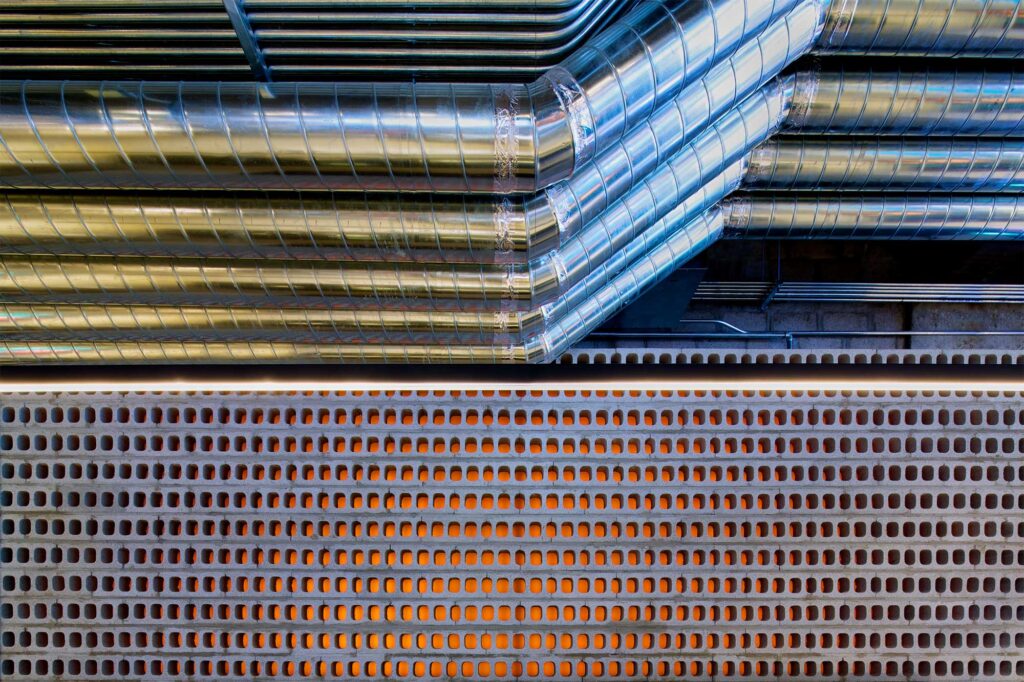 An impressive raw-finished wall featuring pipes, concrete, and LED color lights at Nike's largest store in Korea, displaying the latest sportswear in Gangnam, Seoul.