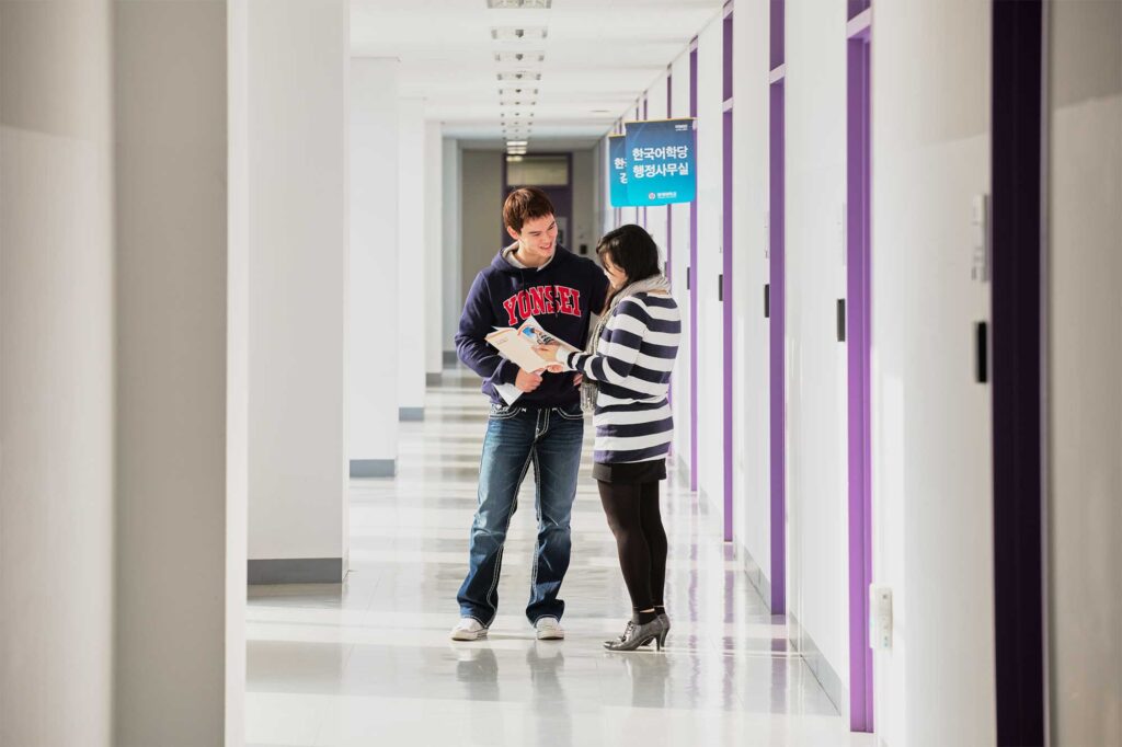 Two students discuss an assignment in a hallway at Underwood International College, Yonsei University, Incheon Songdo Campus, South Korea.