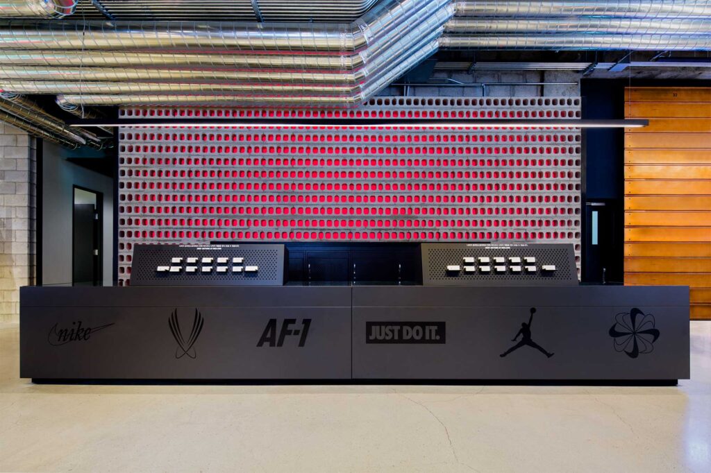 An impressive cashier counter in front of a raw-finished wall with pipes, concrete, and LED color lights at Nike's largest store in Korea, showcasing the latest sportswear in Gangnam, Seoul.