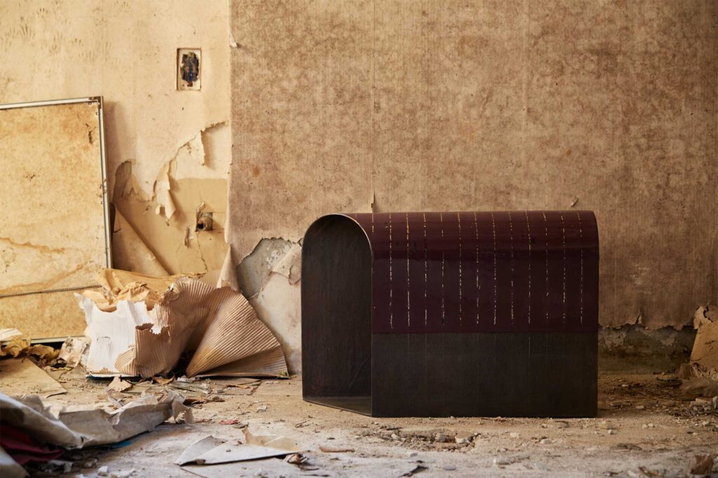 A lacquer-coated bronze furniture piece by Korean artist Kwangho Lee, winner of the 2013 YÉOL Young Craftsman Award, placed in front of a wall in an abandoned, cluttered home in Seoul.