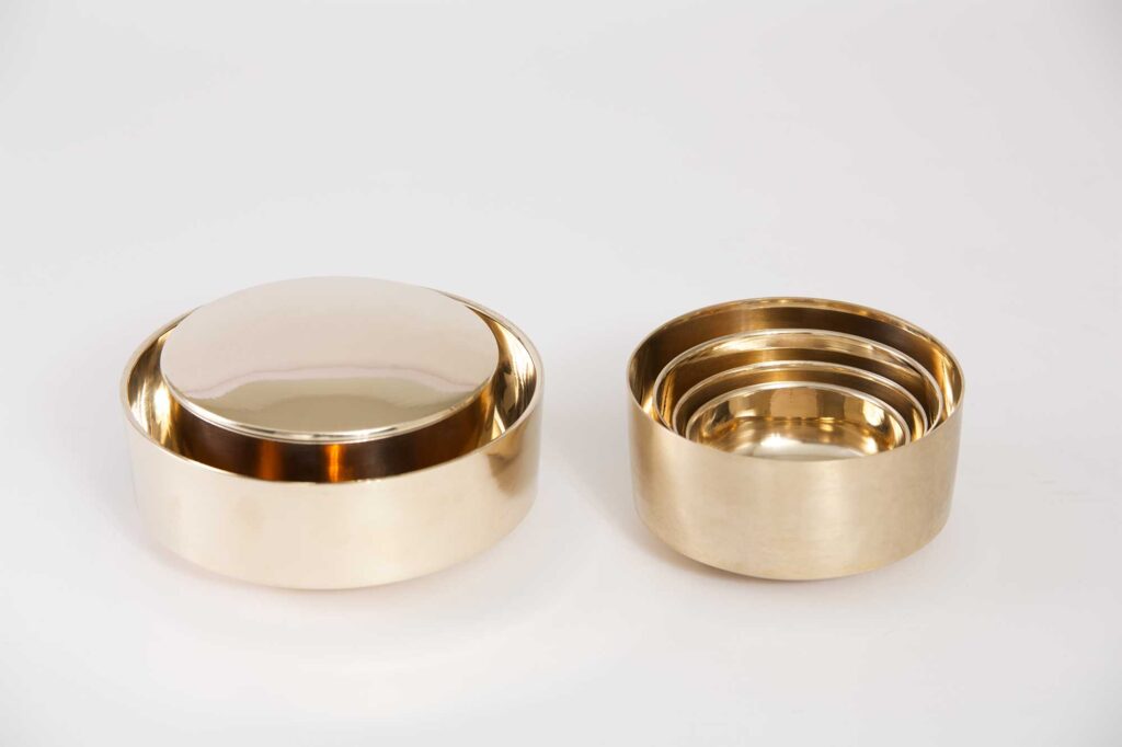 Different sized cylinder-shaped bowls from the Korean traditional brass kitchenware collection designed by Gio Kisang and crafted by YÉOL Artisan of the Year, Kim Soo-Young, nested together.