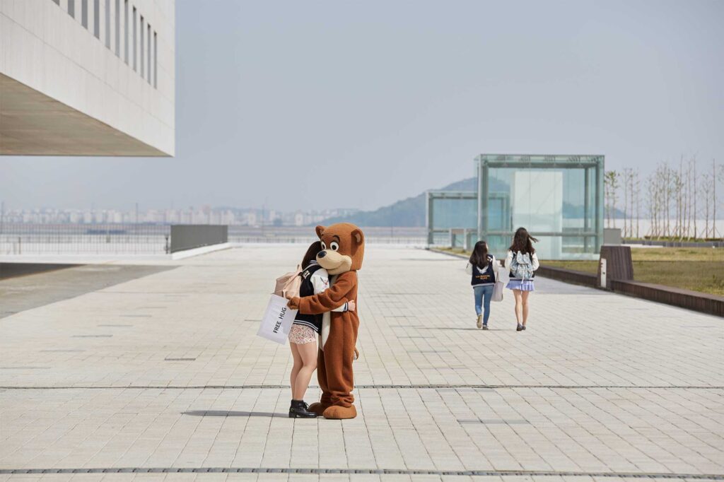 A female Underwood International College student shares a cheerful moment, receiving a free hug from a human-sized walking teddy bear on the Songdo campus of Yonsei University, Seoul, South Korea.